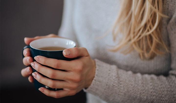 Hände mit Teetasse Hände einer Frau umgreifen eine Teetasse