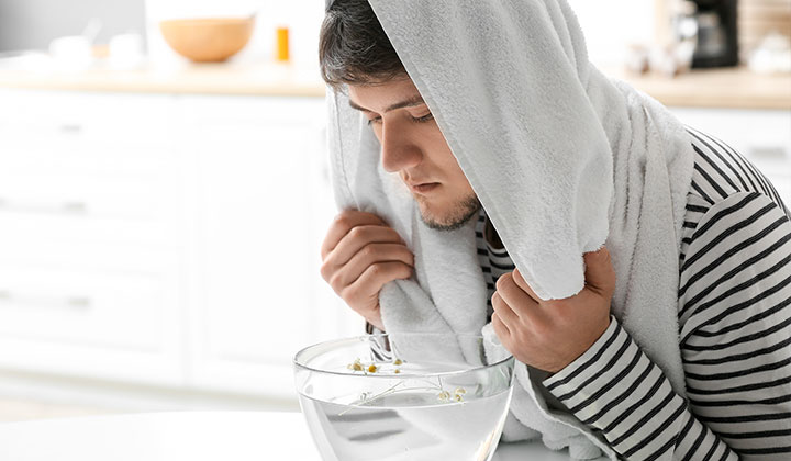 Mann inhaliert über Wasserdampf Mann inhaliert bei Schnupfen über Wasserdampf
