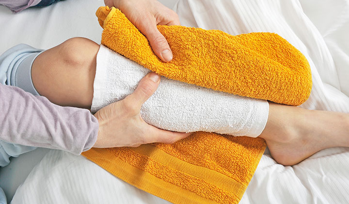 Frau legt Wadenwickel bei Kind Wadenwickel als Hausmittel bei Erkältung